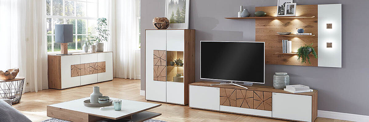 Modernes Wohnzimmer mit stilvoller Wohnwand in Weiß und Holz, dekorativer Beleuchtung und gemütlicher Sofalandschaft.
