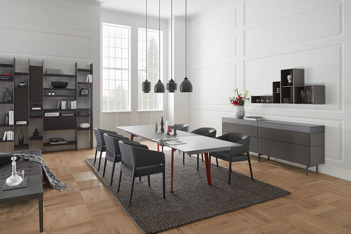 Elegantes Esszimmer von Ambienta mit großem Esstisch, Sideboard und Bücherregal – modernes Einrichtungskonzept in Grautönen mit stilvollen Akzenten.
