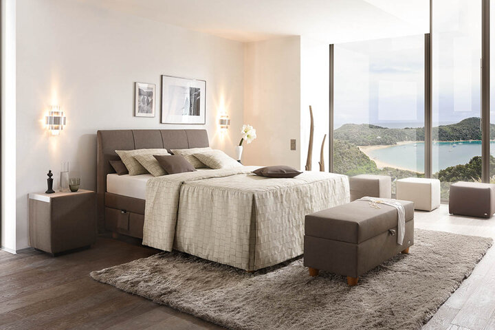 Modernes Polsterbett von RUF Betten mit gepolstertem Kopfteil und integriertem Stauraum in elegantem Schlafzimmerambiente.