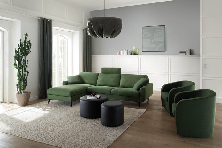 Grünes Wohnzimmer mit Sofa und Sesseln von Erpo, einem modernen Couchtisch und großen Fenstern, die den Blick auf eine grüne Umgebung freigeben.