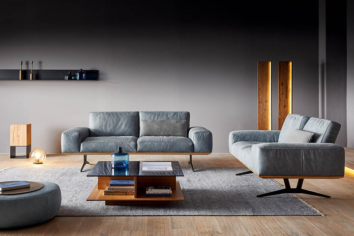 Lässige Lounge-Ecke mit KOINOR-Sofa in hellem Graubeige – ergänzt durch Hocker, Kissen und einen markanten Holztisch für stilvolle Wohnlichkeit.