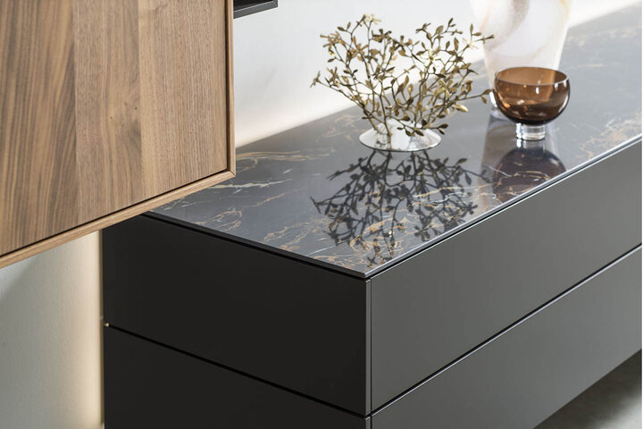 Schwarzes Sideboard von Ambienta mit edler Marmoroptik-Oberfläche – stilvoll dekoriert mit Glasvase und Designobjekten.
