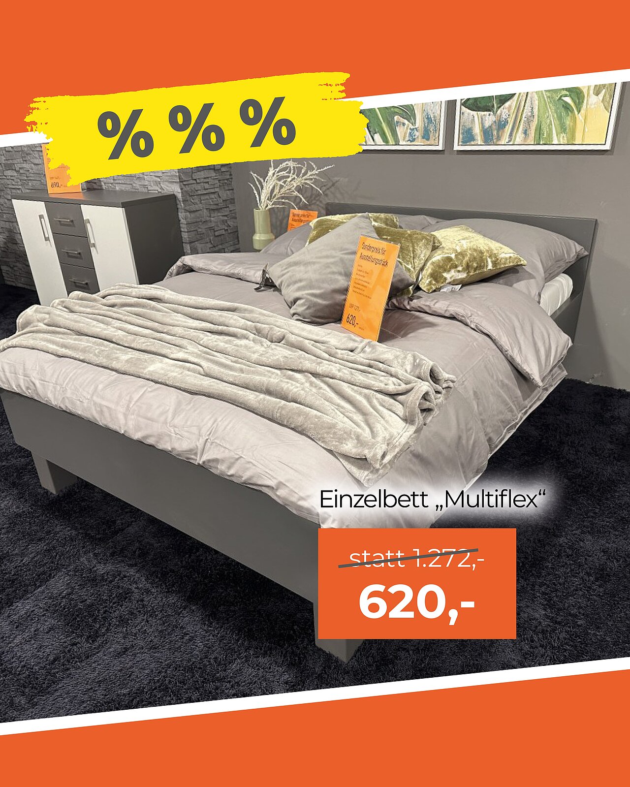 Einzelbett mit grauer Bettwäsche, zwei Kissen und Decke