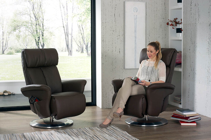 Zwei drehbare Relaxsessel von himolla in dunklem Braunleder auf Chrom-Tellerfuß – ein eleganter Rückzugsort mit natürlichem Ausblick und wohnlicher Atmosphäre.