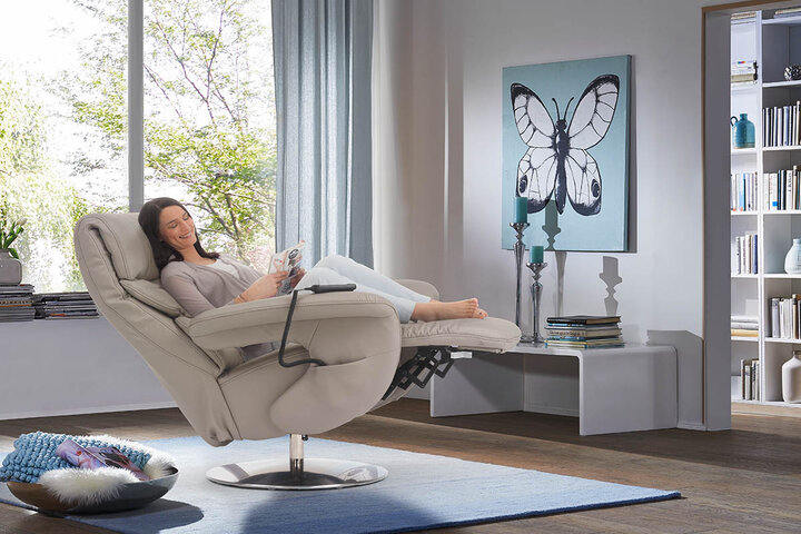 Elektrisch verstellbarer himolla-Relaxsessel in Cremeweiß mit integrierter Fußstütze – hier entspannen Design und Funktion in perfekter Harmonie, wie gezeigt im hellen, wohnlichen Raum mit Bücherregal.