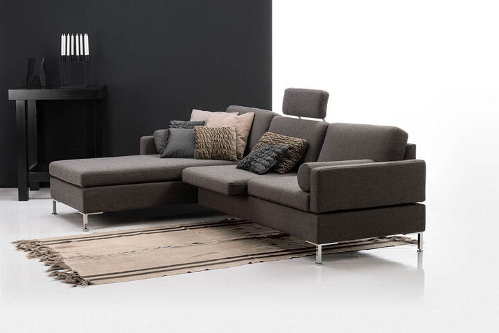 Dunkelgraues Ecksofa von brühl mit Kopfstütze und vielen Kissen.