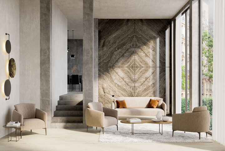 Sofa-Arrangement von JORI in samtigem Beige mit passendem Sessel – kunstvoll inszeniert vor großflächiger Natursteinwand und bodentiefen Fenstern im urbanen Loft-Stil.