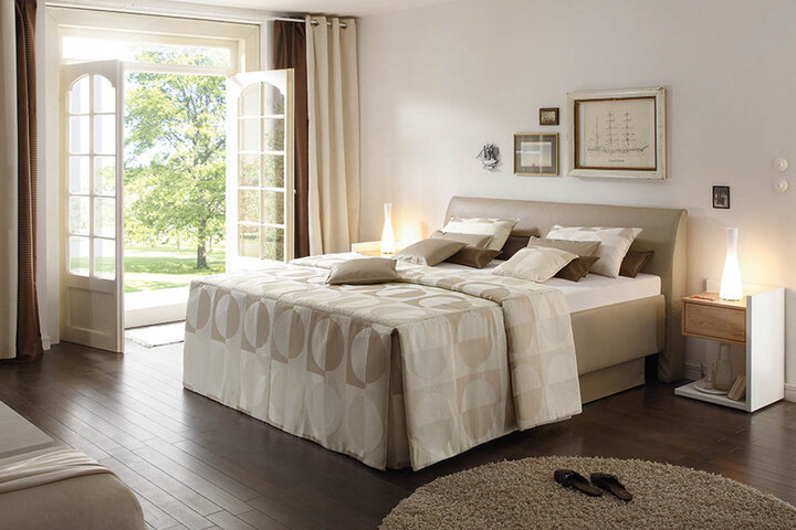 Hochwertiges Boxspringbett von RUF Betten mit gepolstertem Kopfteil und stimmungsvoller Beleuchtung.